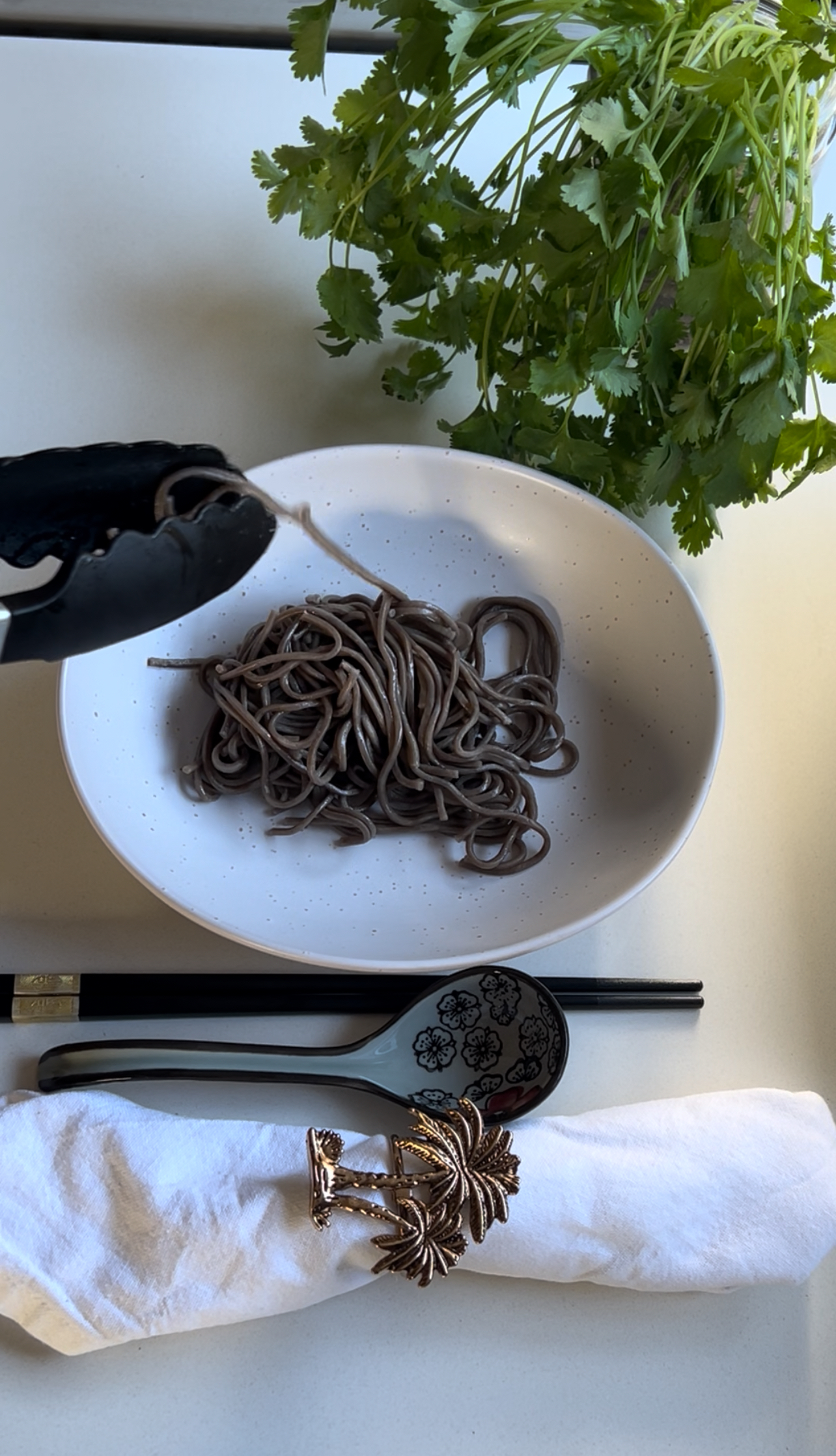 Soba or ramen noodles boiling in a separate pot with steam rising.