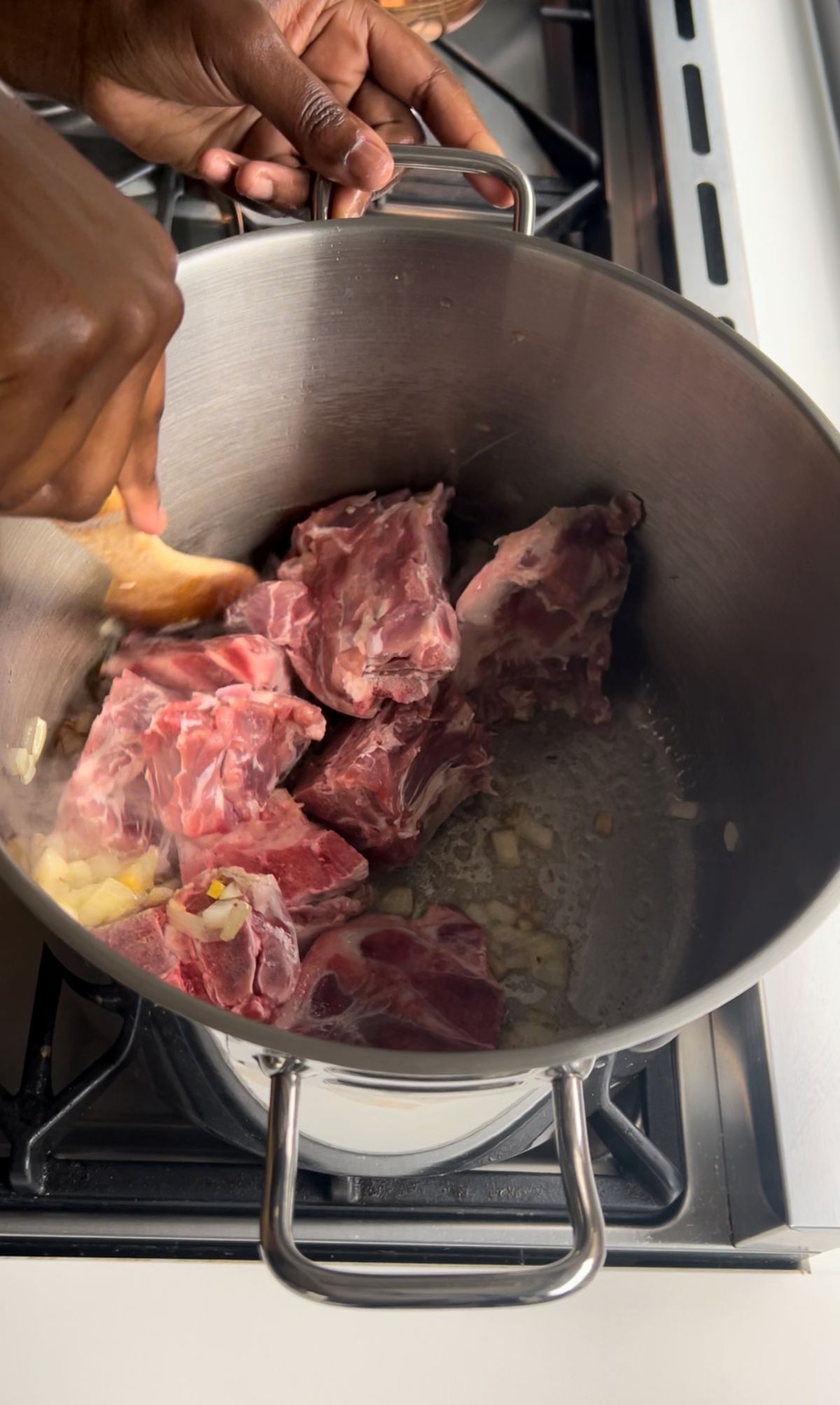 Thinly sliced pork is cooking in a large pot until golden, surrounded by fragrant aromatics.