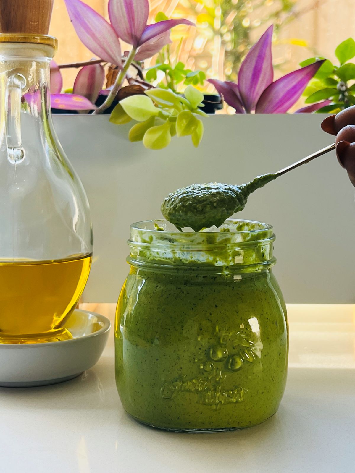 scoop-of-coriander-pesto-recipe A spoon scooping homemade pesto from a jar, highlighting the creamy texture of the coriander pesto recipe.