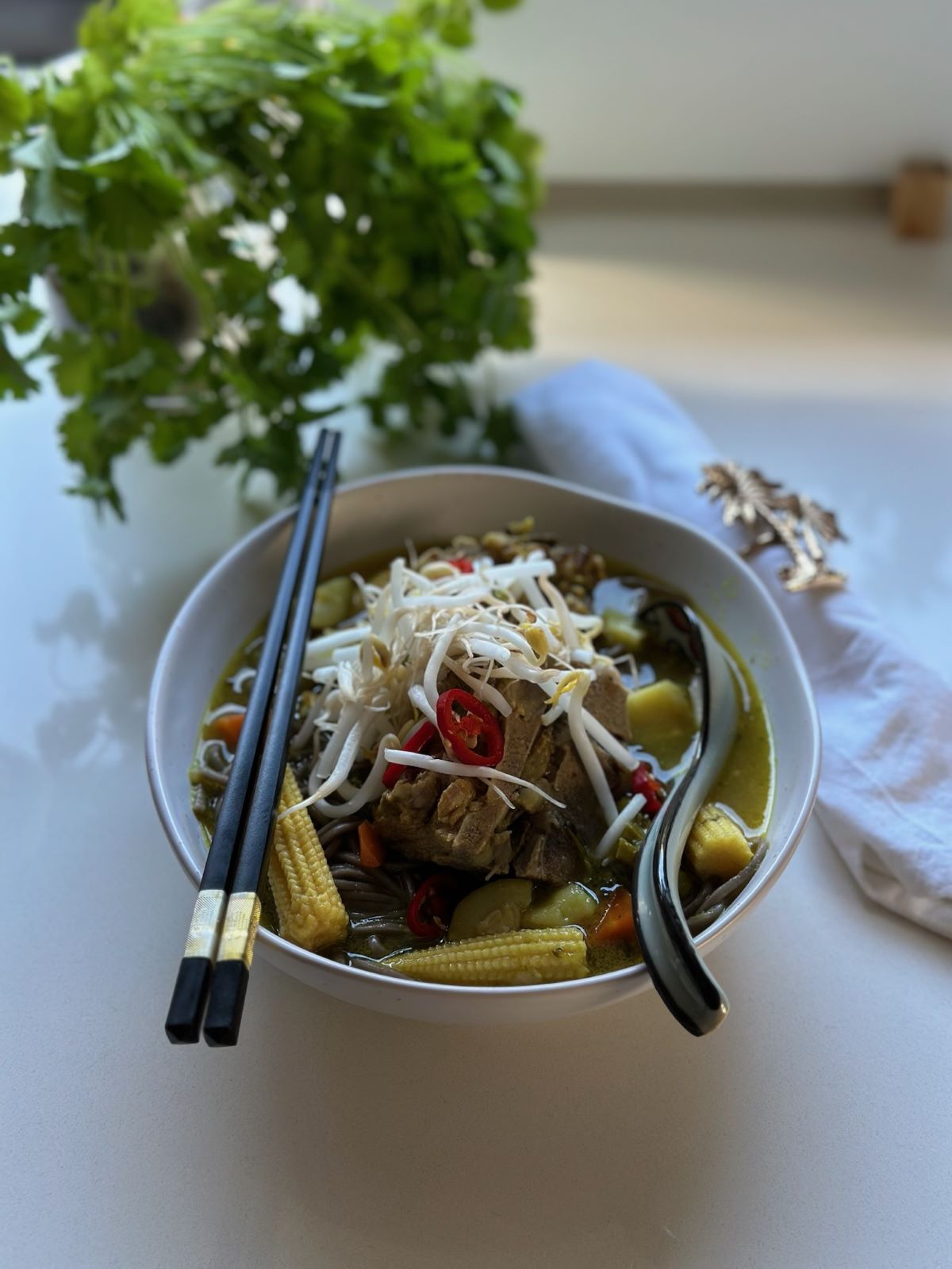 A steaming bowl of Japanese-style pork noodle soup served with spring onions, bok choy, and chilli oil—perfect for a cosy, nutritious family dinner.